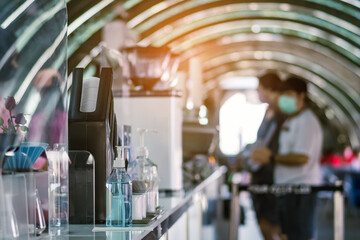 Blue alcohol gel bottle for hand cleaning to prevent the spreading of the Coronavirus (Covid-19) on counter to service for customers at cafe or coffee shop. Healthcare concept. New normal lifestyle.