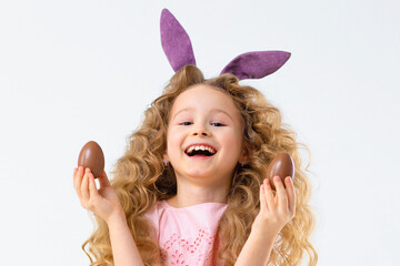 Obraz na płótnie Canvas Happy holiday easter kids. Smiling cute little beautiful girl with rabbit hare bunny ears playing with chocolate eggs