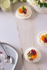 dessert pavlova with cream and fruits on gray plate white scandic ground white spring flowers matcha tea