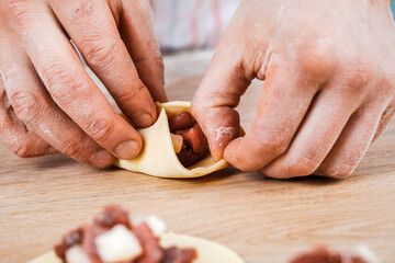 A man is holding a khinkali in close-up. Cook in the kitchen. The process of preparing a national dish.