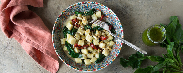 bowl of italian potato gnocchi with spinach and sundried tomatoes on the table - obrazy, fototapety, plakaty
