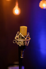 Fototapeta na wymiar Professional microphone in a recording audio studio with acoustic panels behind it, and blue light on a background.