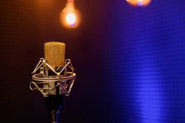 Professional microphone in a recording audio studio with acoustic panels behind it, and blue light...