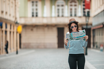 Happy young woman with a city map in city. Travel tourist woman with map outdoors during holidays in Europe.
