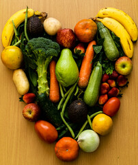 Healthy heart based on fruits and vegetables to have a quality life, for good eating habits: apples, avocado, bananas, green beans, pumpkins, strawberries, potatoes, oranges, carrots. 
