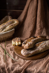 Homemade bread on a wooden board and in a basket on a brown background. Bakery. Fresh, aromatic, hot bread