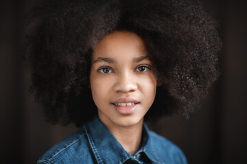 Happy beautiful African American teenage girl with Afro hairstyle looking at camera with toothy smile. Face portrait.