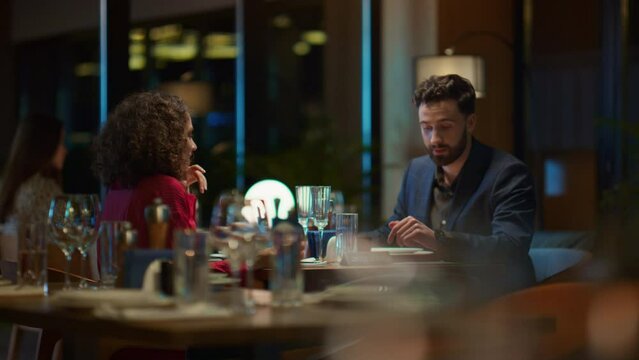 Multiethnic couple enjoying romantic dinner date in elegant night restaurant.
