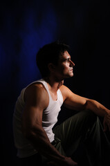 The sexy man is posing in a studio with a dark background. 