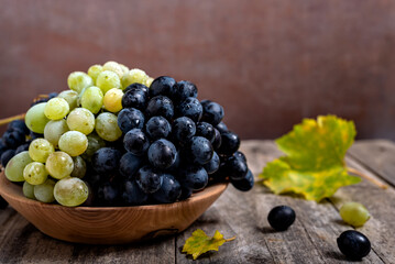 Bowl with grapes on wooden background