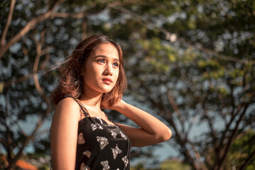A slim, petite and pretty young Filipina wearing a black butterfly print spaghetti strap top at the...