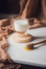 Milk and honey. Glass cup with milk and bowl with honey on the table. Spoon for honey. Breakfast, snack. Calming and healthy drink.