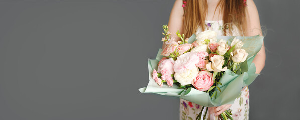 Woman holding a beautiful bouquet with flowers on grey background. Front view. Valentine's, women's, mother's day, love concept. 8th of march. Banner