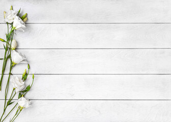 White wooden background and white flowers of Eustoma or Lisianthus on the left side, top view flat lay