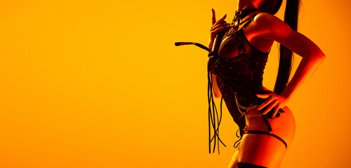 Fototapeta Studio shot of sexy young woman wearing leather lingerie posing isolated on yellow background in neon light. Concept of beauty, love obraz