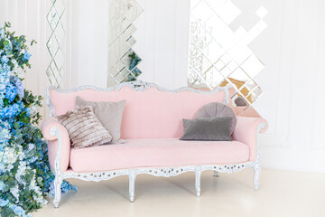 Beautiful luxury classic clean interior living room in white color with pink sofa flower cmposition. Bright modern stylish interior living room with furniture in classic minimalist style