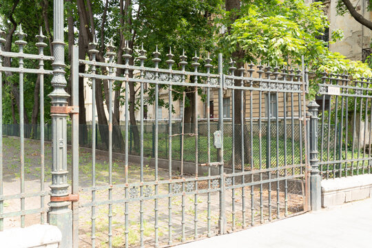 Delicate metal gate with beautiful little iron flowers and fountain with an iron lock to provide security for a museum in Bucharest. Rust amplifies its vintage look. Fixing is very much needed here.