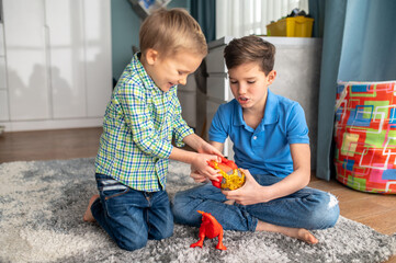 Two kids with rubber animal figures sitting in a room