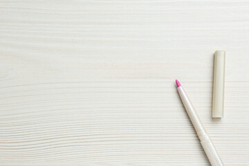 Bright lip pencil on white wooden table, flat lay. Space for text