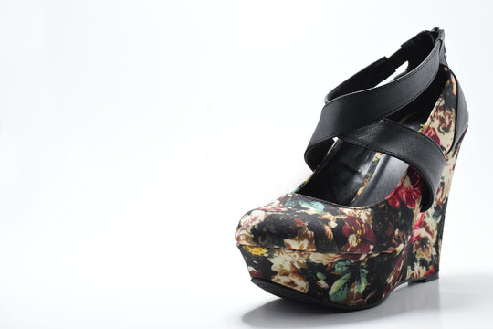 Zapato negro de plataforma con diseño de flores de colores. Zapatos de mujer sobre un fondo blanco con espacio para texto al lado izquierdo.