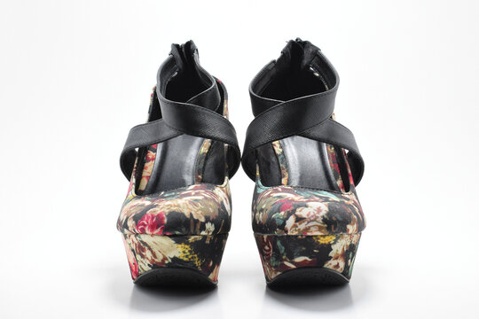 Zapatos negros de plataforma con diseño de flores de colores. Zapatos de mujer sobre un fondo blanco, vista frontal.