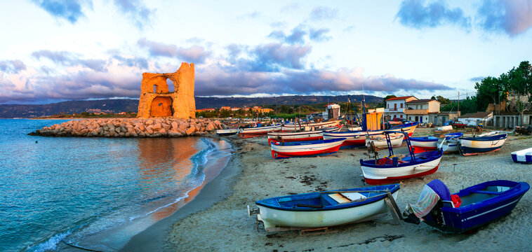 Picturesque beach scenery with tradtional fishing boats and saracen tower in Calabria. Landmarks of south Italy