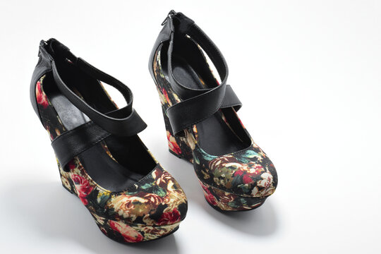 Zapatos negros de plataforma con diseño de flores de colores. Zapatos de mujer sobre un fondo blanco con espacio para texto al lado derecho., vista superior.
