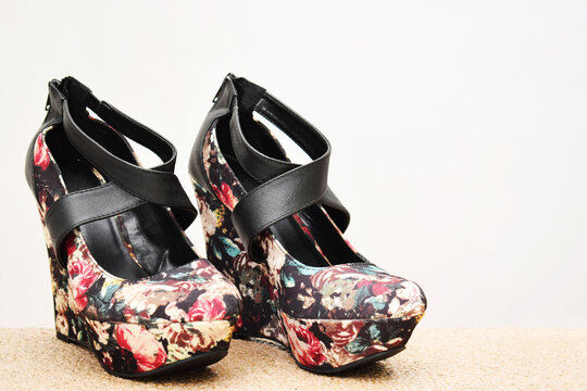 Zapatos negros de plataforma con diseño de flores de colores. Zapatos de mujer sobre un fondo blanco con espacio para texto al lado derecho.