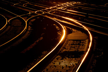 Railway tracks glowing in warm evening light. Metal reflecting orange sky at Dortmund Main Station...