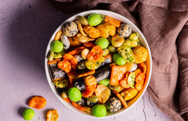 Various Japanese snacks in a wooden bowl close-up. Rice crackers with wasabi and nori, peanuts with sesame seeds, and other snacks. Mix traditional Japanese snack food.