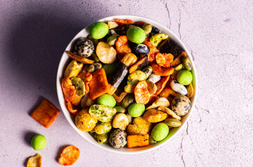 Various Japanese snacks in a wooden bowl close-up. Rice crackers with wasabi and nori, peanuts with sesame seeds, and other snacks. Mix traditional Japanese snack food.