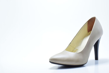 Zapato de tacón para mujer color beige. Calzado formal para fiesta o trabajo sobre un fondo blanco, espacio para texto al lado izquierdo.