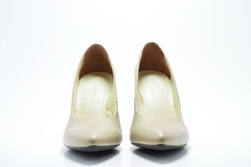 Zapatos de tacón para mujer color beige. Calzado formal para fiesta o trabajo sobre un fondo blanco, vista frontal.