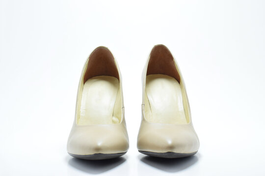 Zapatos de tacón para mujer color beige. Calzado formal para fiesta o trabajo sobre un fondo blanco, vista frontal.
