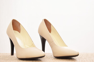 Zapatos de tacón para mujer color beige. Calzado formal para fiesta o trabajo sobre un fondo blanco, espacio para texto al lado derecho.