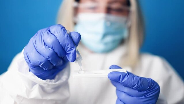 Close up of a doctor in medical PPE suit holds COVID-19 coronavirus PCR test