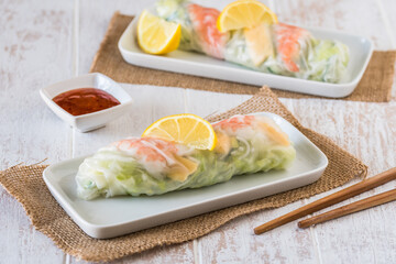 Two summer rolls with salad and prawns on a white wooden background, japanese, asian food
