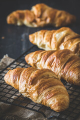 Row of delicious French croissants on black background, vertical