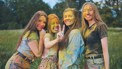 Cheerful girls posing smeared in multi-colored powder.