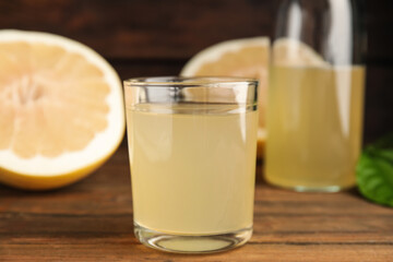 Glass of fresh pomelo juice on wooden table, closeup