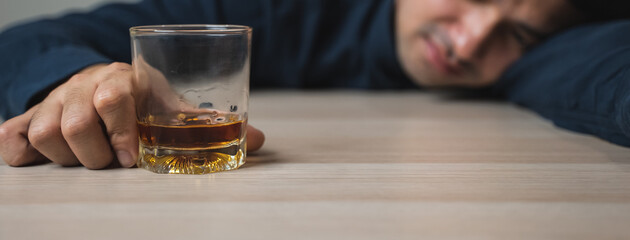 drunk man fall asleep on the table with whiskey glass