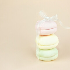 Colorful marshmallows looks like french macarons with white ribbon bow, close up. Concept of sweet dessert gift, colorful cookies, pastel colors.