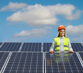 Young female engineer posing between solar panels