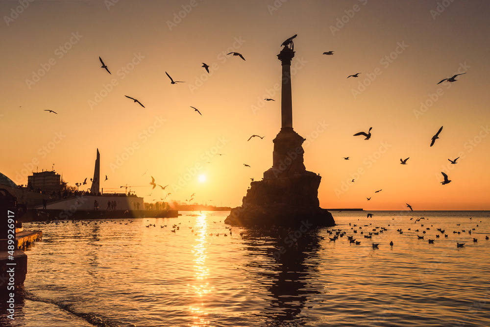 Wall mural sunset on embankment of sevastopol. monument to sunken ships against the sun. sevastopol, crimea