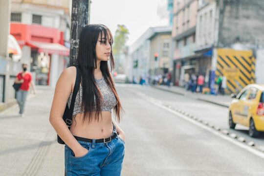 beautiful brown-skinned latina girl standing by the roadside in the city of Pereira-Colombia. young university student thinking about her degree project while waiting for someone else.