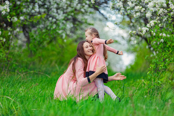 Naklejka na ściany i meble mother and daughter hugging against the backdrop of flowering trees