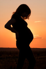 Pregnant woman at sunset. Contrast photo.