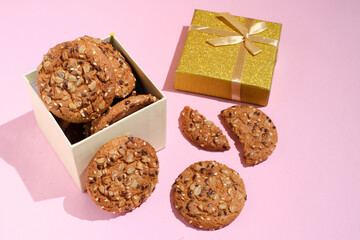 oatmeal cookie in gift box over pink background with copy space. Gift box of cookies with shadows and sunlight.