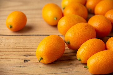 Top view of a group of kumquats on rustic wooden table, with selective focus, horizontal, with copy space