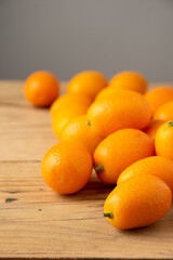 Close-up of a group of kumquats on a rustic wooden table, gray background, with selective focus, vertically, with copy space
